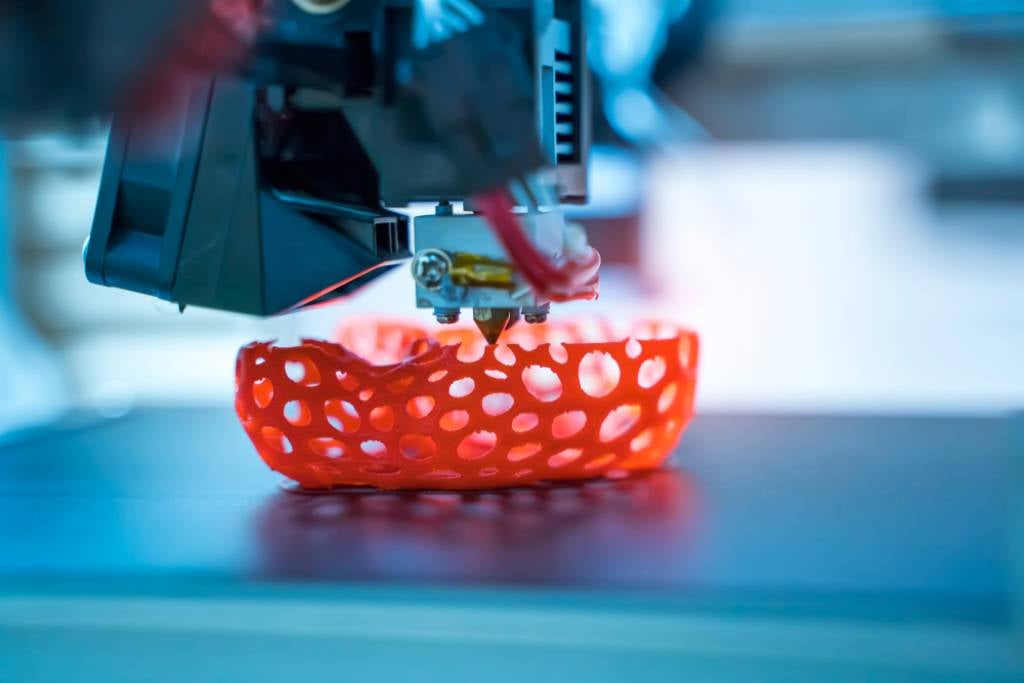 3D printer creating an orange object with complex design