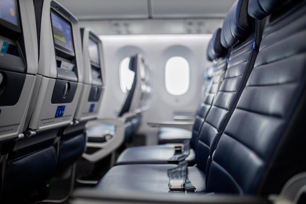 Airplane-interior-with-empty-dark-blue-seats-with-screens-in-the-back