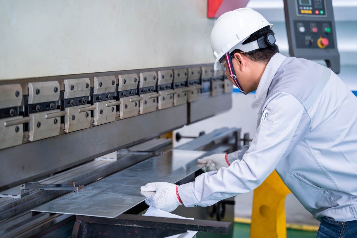 Technician-worker-wearing-a-safety-suit-and-sheet-metal-bending-in-industrial-factory