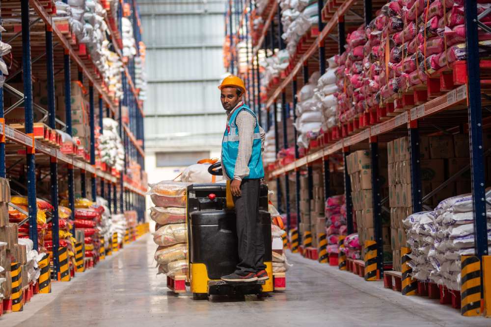 Worker with a cart of items in a warehouse