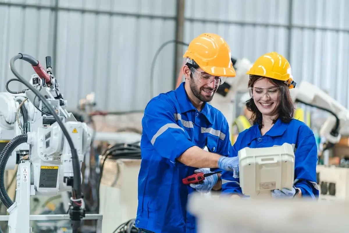Two workers in PPE next to a robotic instrument.