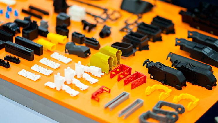 small plastic parts laid out on orange table using injection molding method