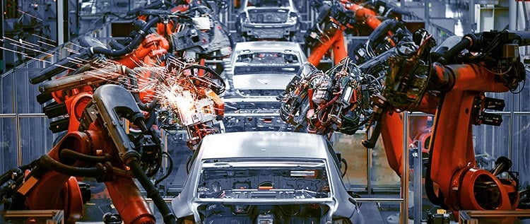 Robotic arms work on manufactured cars in low volume production facility