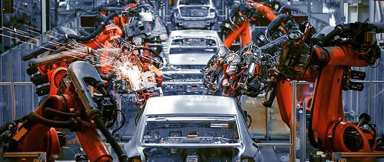 Robotic arms work on manufactured cars in low volume production facility