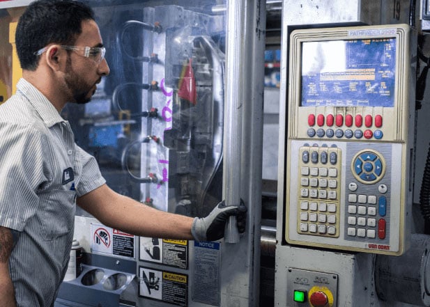 A man using a machine for low volume plastic injection molding service