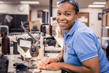 A seamstress smiles while sewing automotive leather seat covers. A seamstress smiles while sewing automotive leather seat covers.