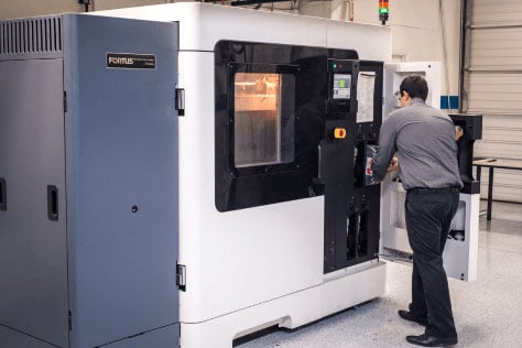 A man working a statasys fdm machine for additive manufacturing services        